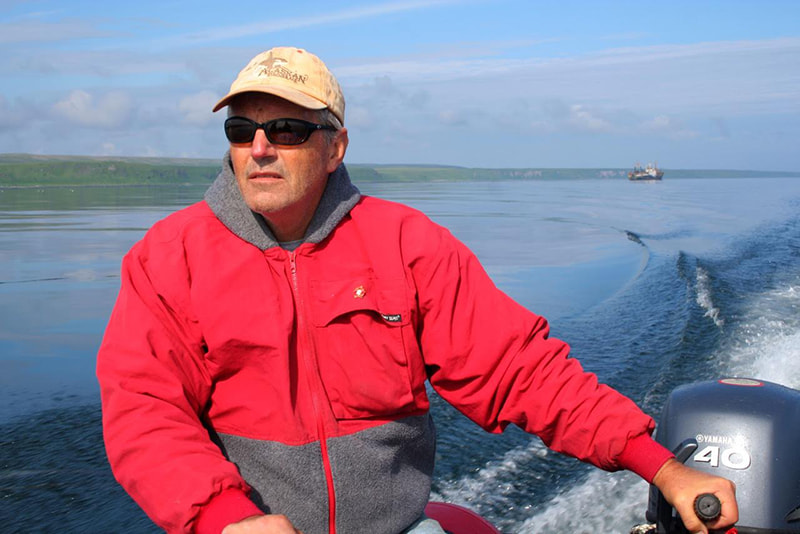 Dr. James Estes in a red jacket steering a boat.