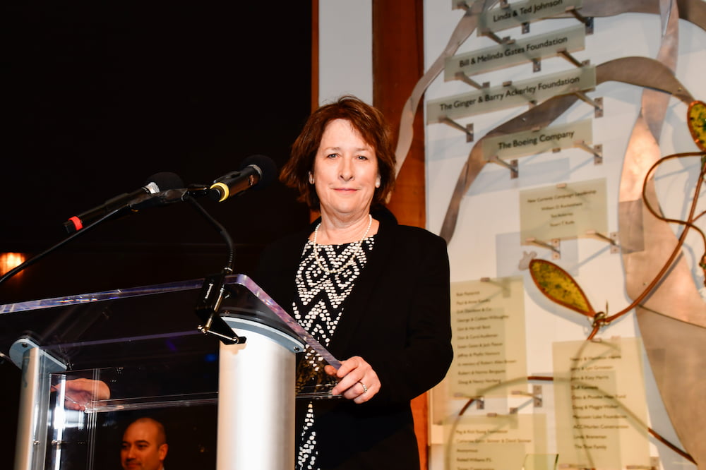 Dr. Vera Trainer standing behind a podium, smiling for a photo while speaking at the Seattle Aquarium's 2023 Ocean Conservation Honors event.