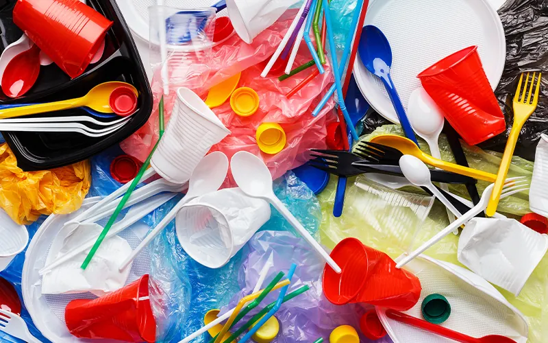 A pile of plastic silverware, plates, cups, straws, and other commonly used items made from plastics.