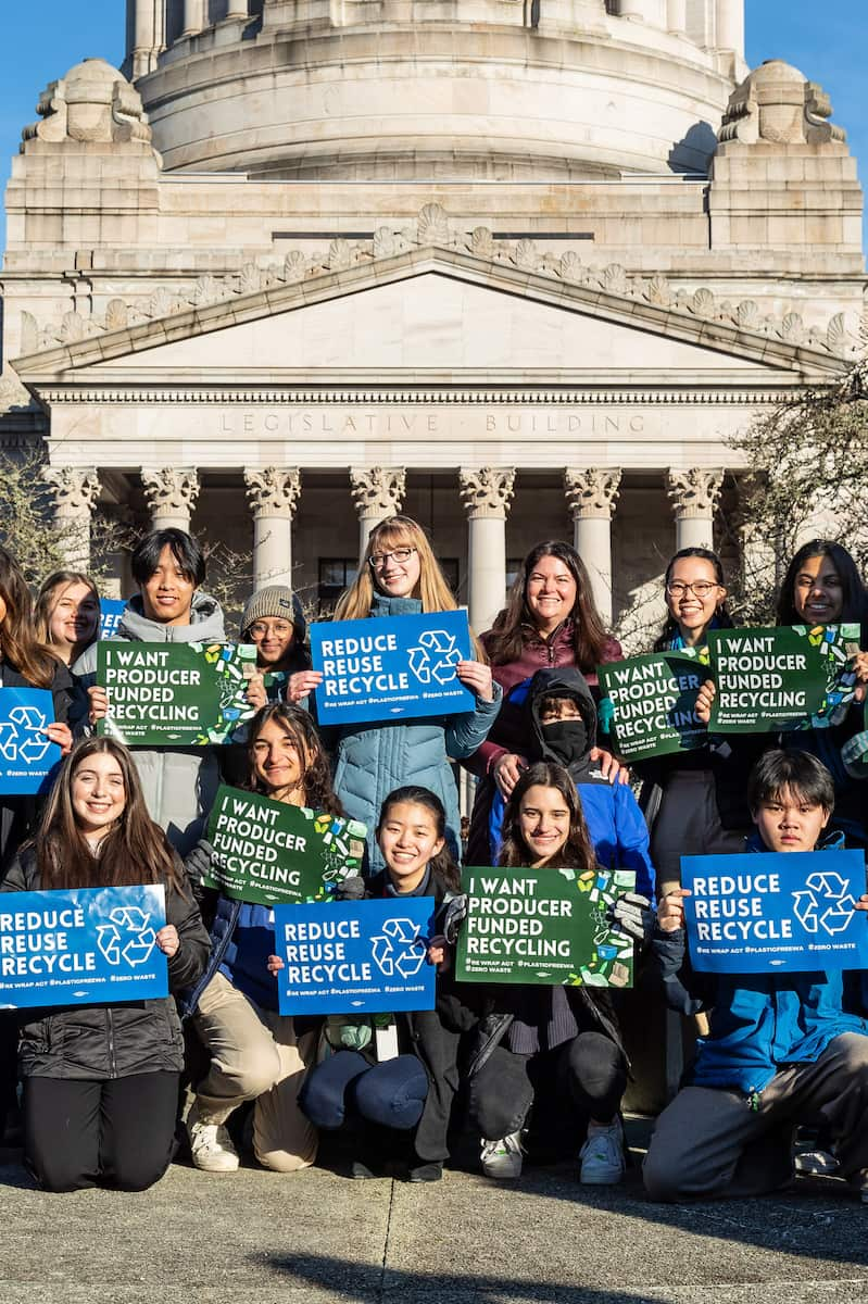 A group of Youth Ocean Advocates holding recycling signs outside of the Washington capitol building.