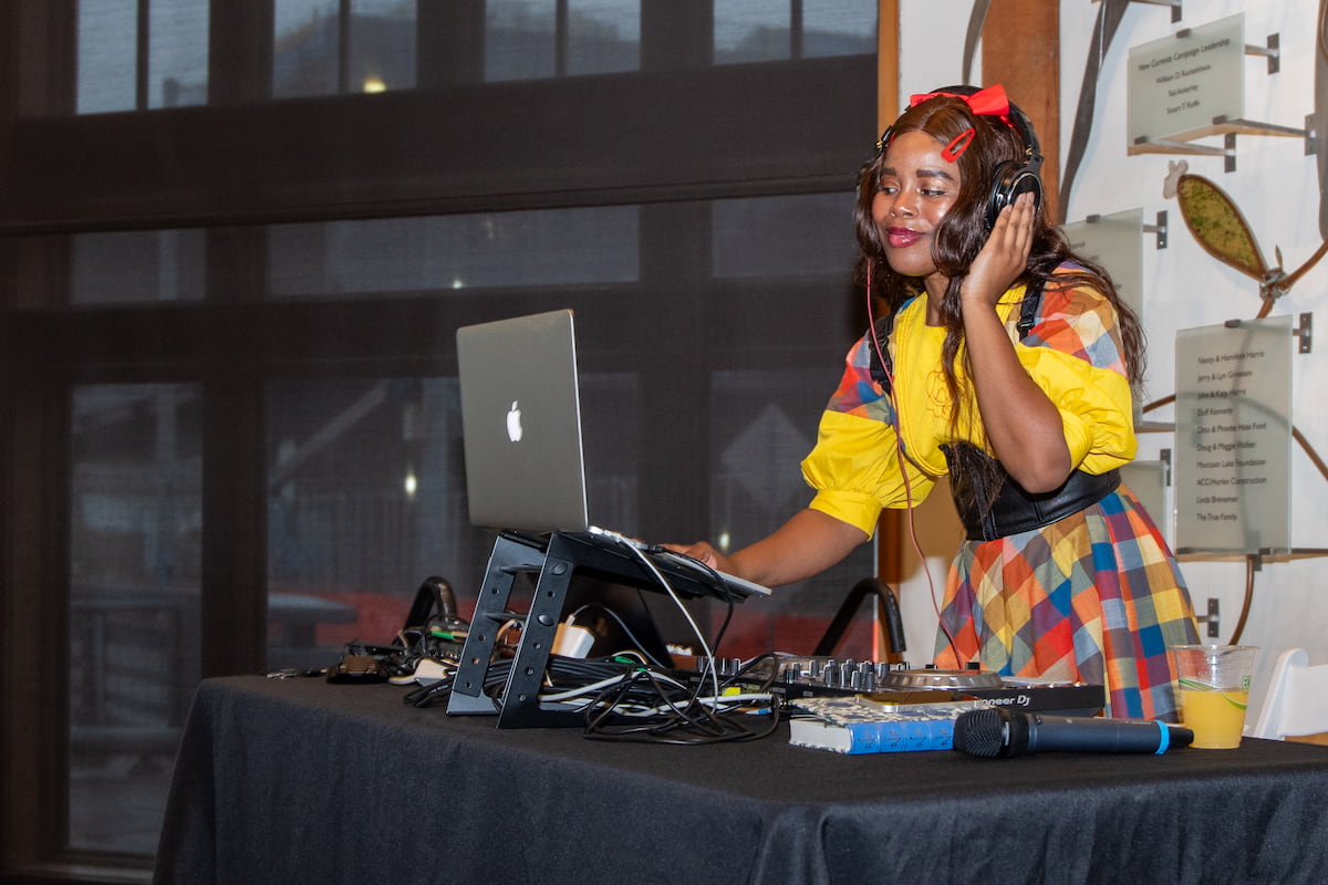 A person in a yellow dress DJing at the Aquarium.