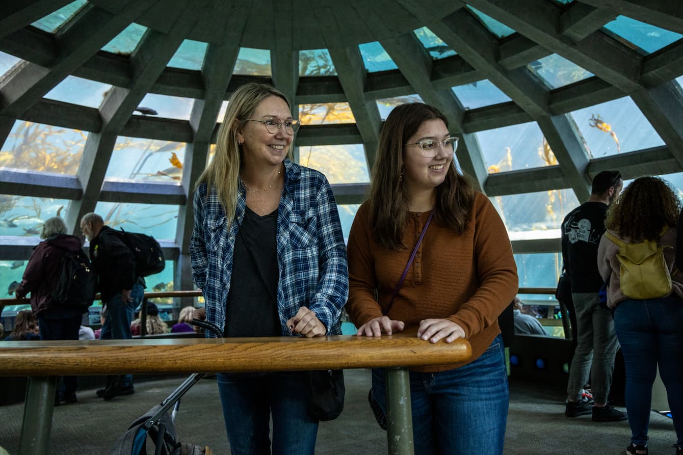 Two women smiling as they explore the Seattle Aquarium's Underwater Dome habitat.