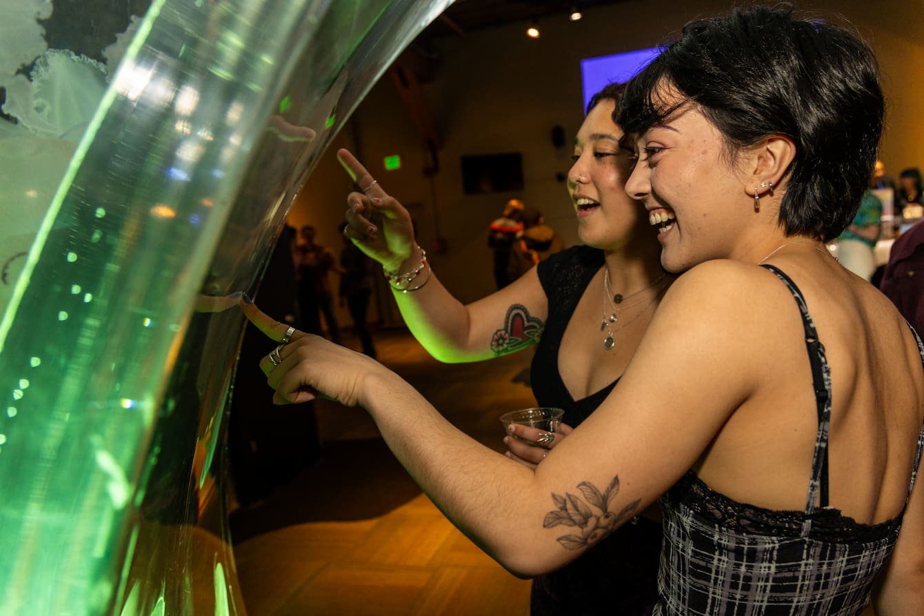 Two people smiling and pointing at the jelly habitat.