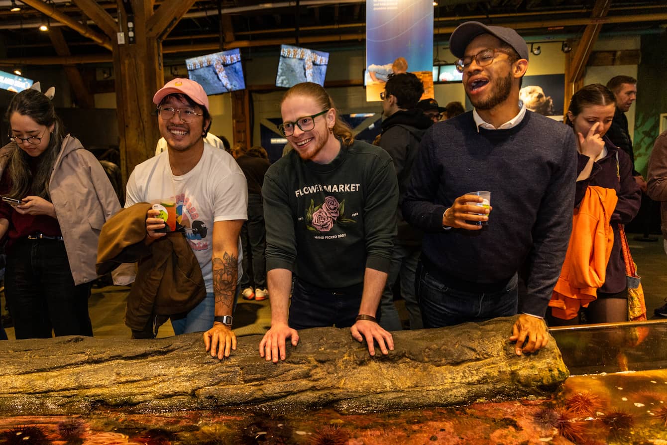 Three people smiling at the touch pools.