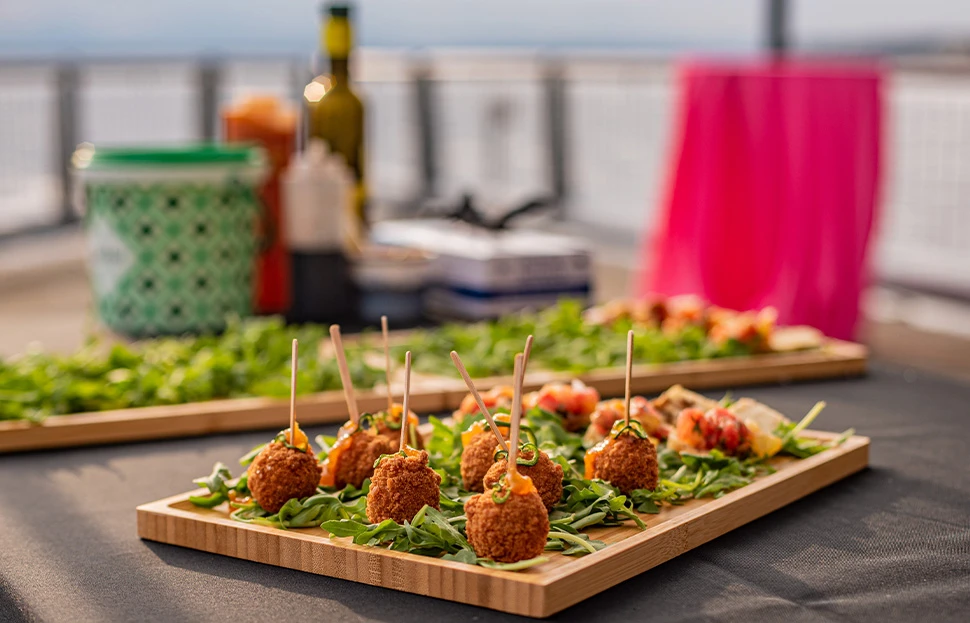 Small bites of fried food, with toothpicks sticking out from inside the top of each individual item, sitting on a wooden serving tray.